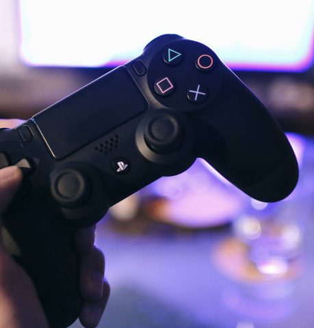 pexels photo 21067 Person holding a gaming controller, blurred screen in background.